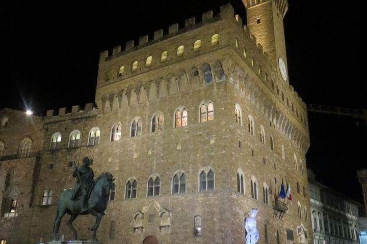 a group of people standing in front of a castle with Palazzo Vecchio in the background