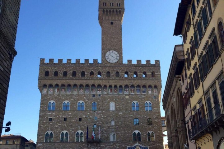 a group of people walking in front of a castle with Palazzo Vecchio in the background